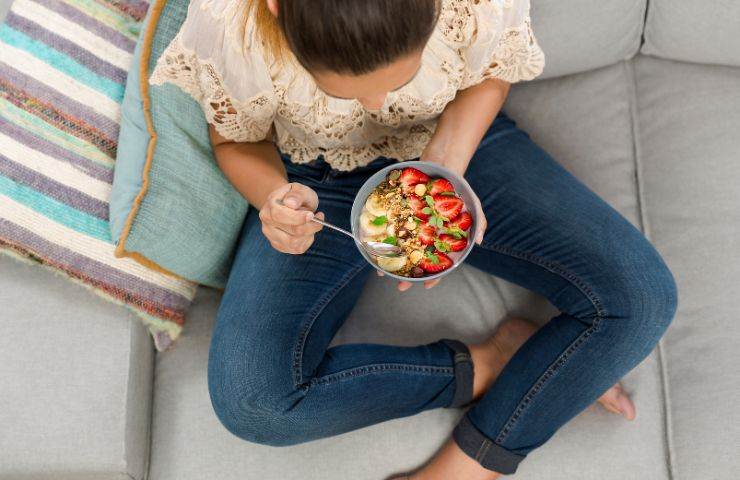 Ragazza consuma ciotola con frutta fresca