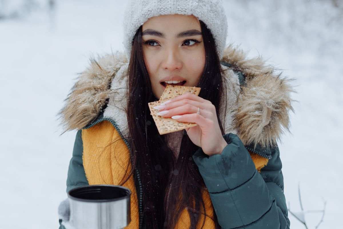 Ragazza mangia all'aperto in paesaggio invernale