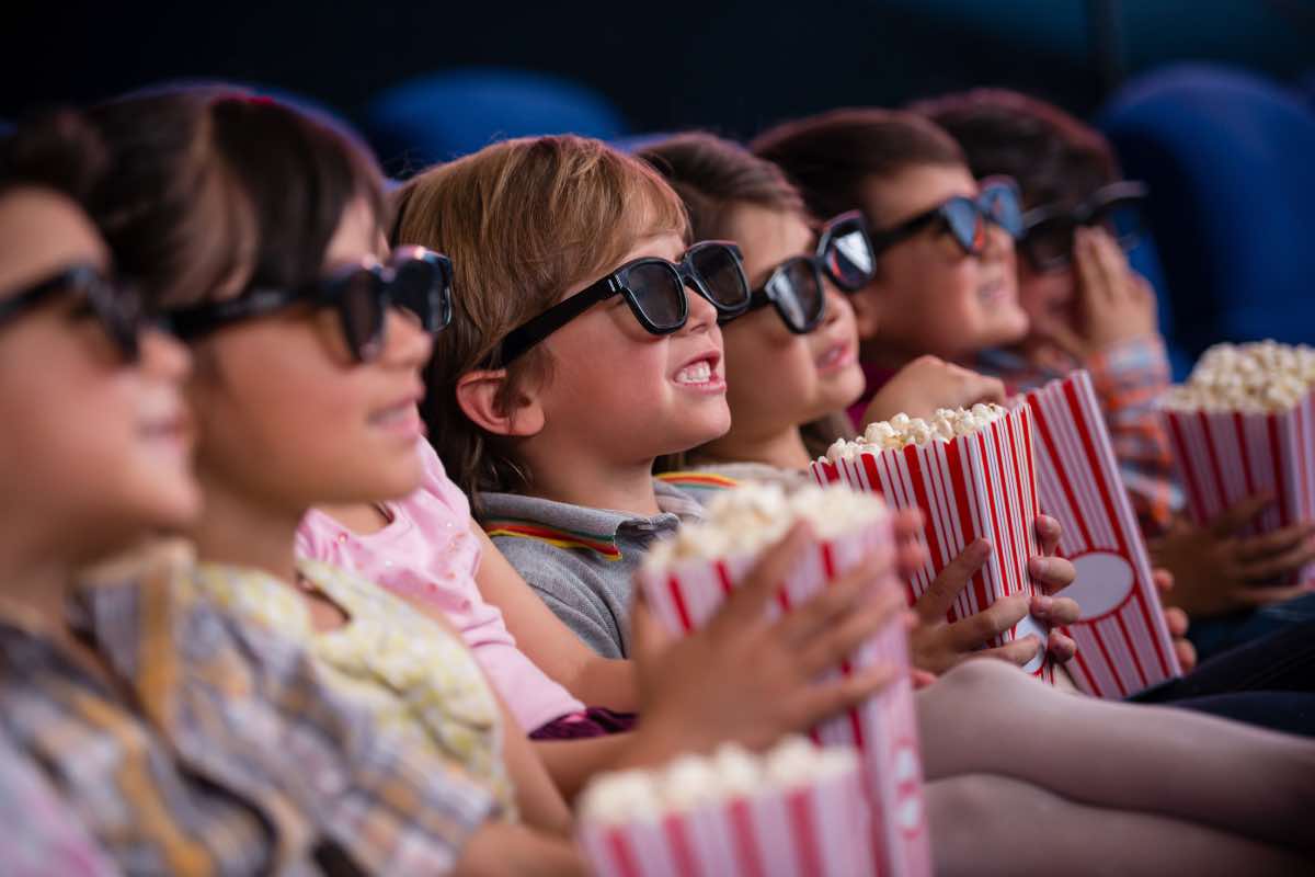 Fila di bimbi con occhiali 3D e popcorn al cinema